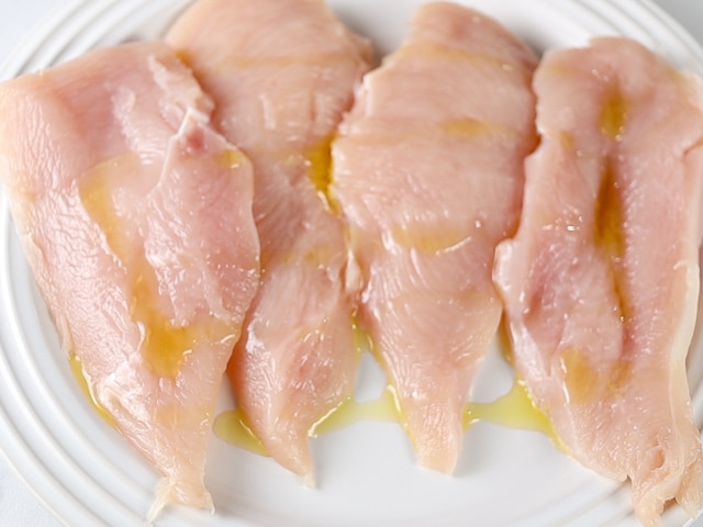 Raw chicken with olive oil drizzled on it