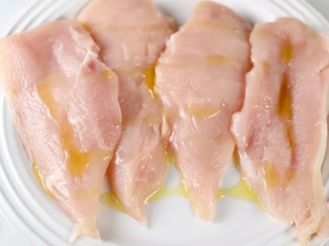 Raw chicken with olive oil drizzled on it