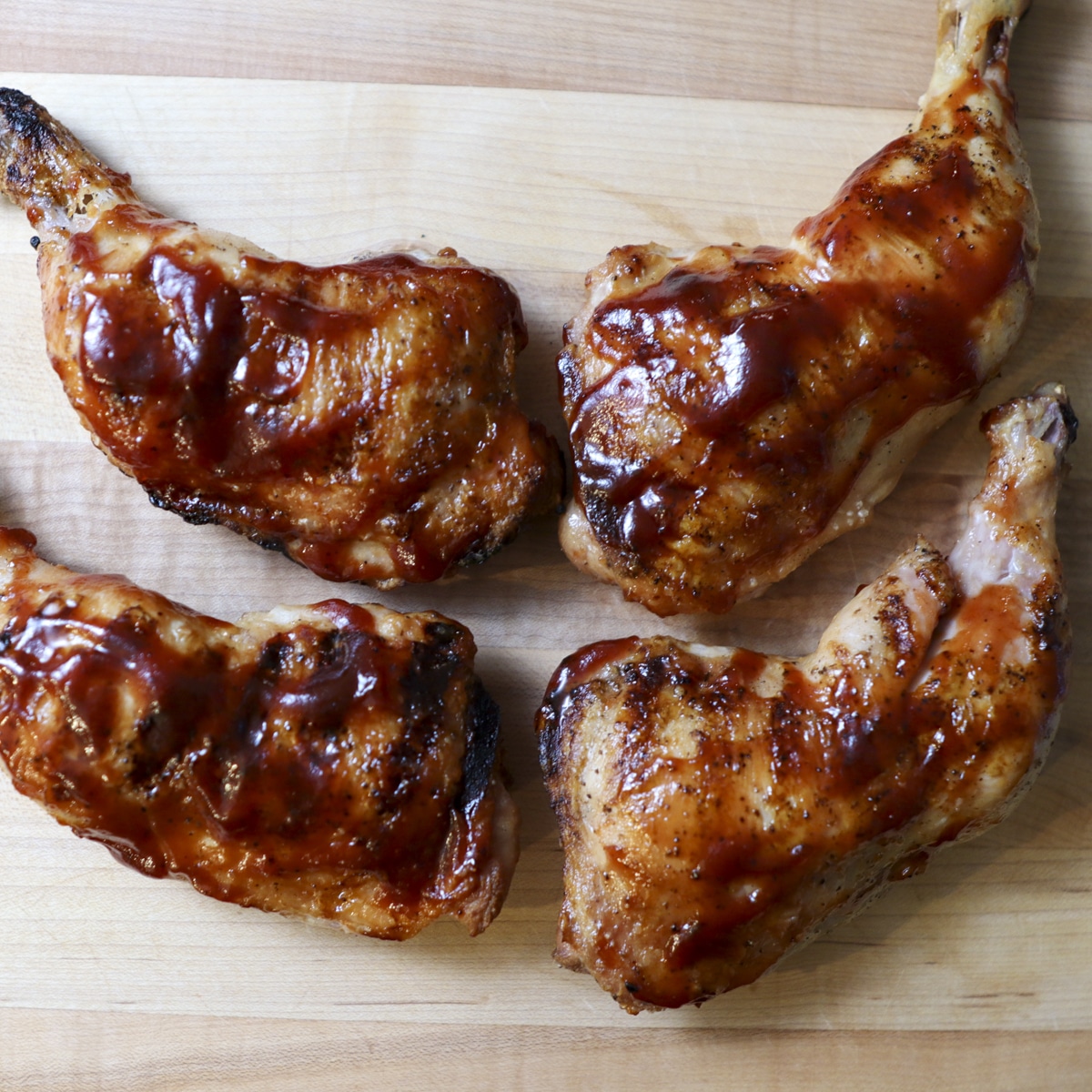 grilled chicken leg quarters on a cutting board
