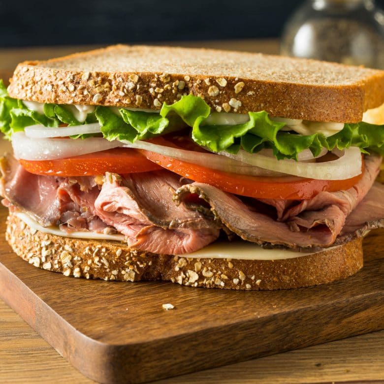 Roast beef sandwich with lettuce, tomatoes, onions and mayo on wheat bread