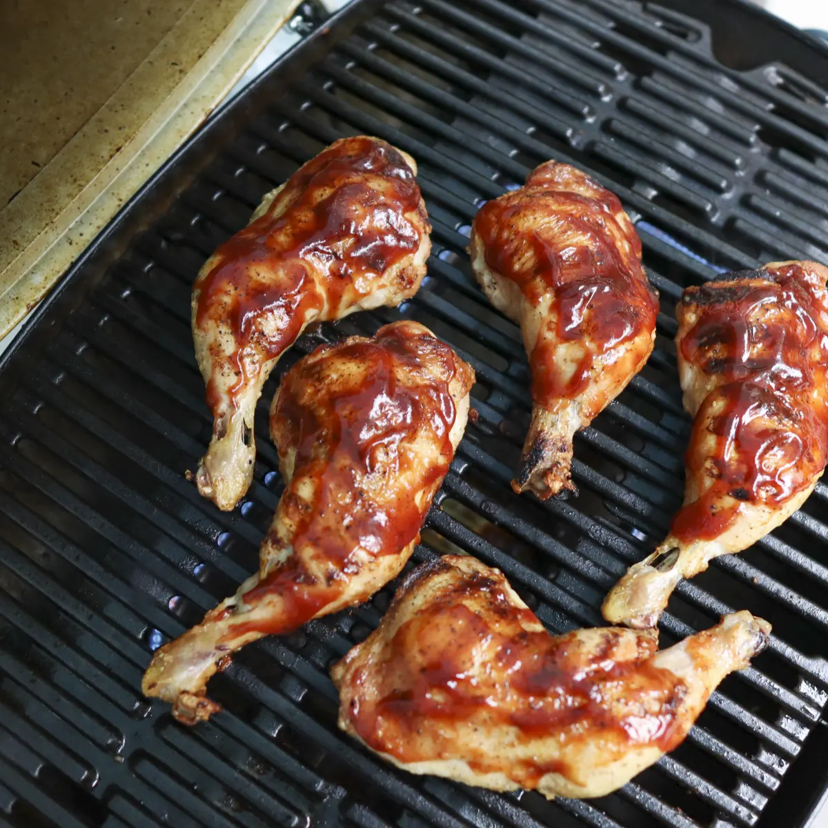 chicken leg quarters with bbq sauce on a grill
