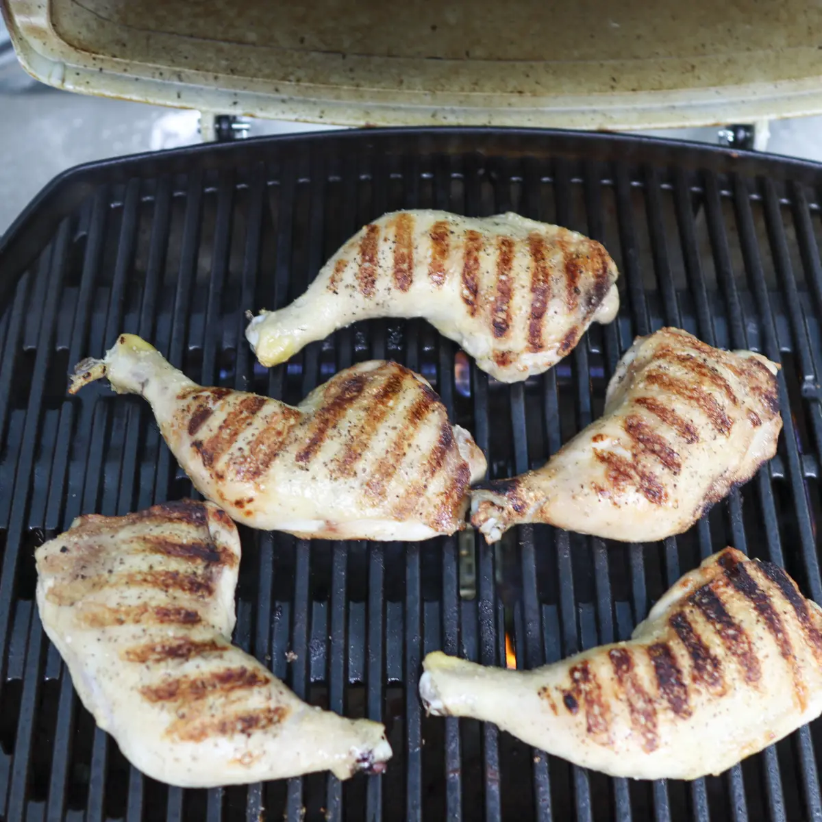chicken leg quarters grilling on a grill
