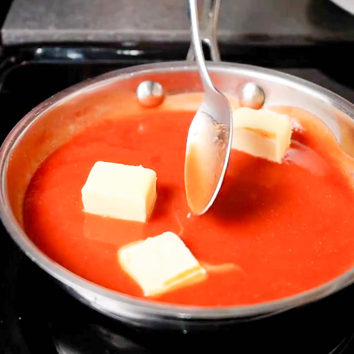 adding and mixing the butter to the hot sauce