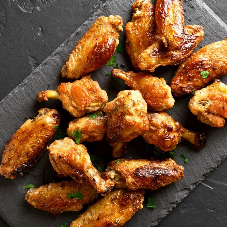 Grilled marinated chicken wings on a slate board.